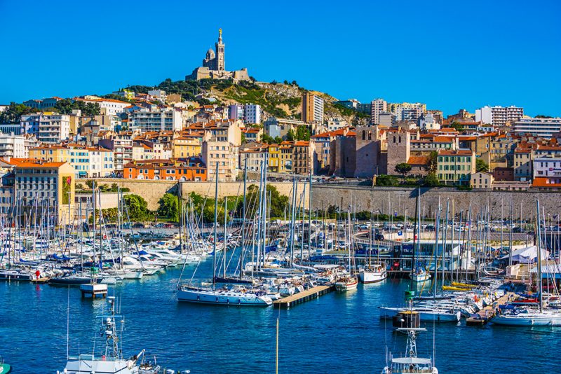 Marseille in May. The water area of the Old Port - yachts, speedboats and fishing boats. On the hill - splendid Basilica of Notre-Dame de la Garde
