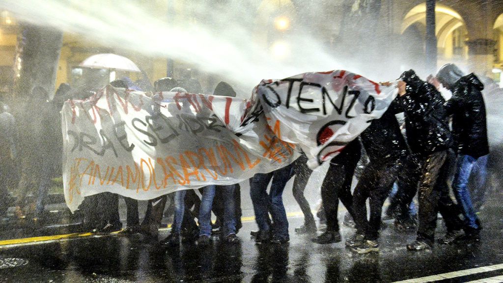 Antifascist activists protect themselves from water cannon used by police officers during a rally against an election campaign meeting organized by far-right movement CasaPound on February 22, 2018 in Turin.