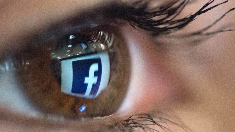 An illustration picture taken on March 22, 2018 in Paris shows a close-up of the Facebook logo in the eye of an AFP staff member posing while she looks at a flipped logo of Facebook.  / AFP PHOTO / Christophe SIMON