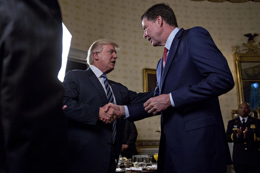 WASHINGTON, DC - JANUARY 22: U.S. President Donald Trump (C) shakes hands with James Comey, director of the Federal Bureau of Investigation (FBI), during an Inaugural Law Enforcement Officers and First Responders Reception in the Blue Room of the White House on January 22, 2017 in Washington, DC. Trump today mocked protesters who gathered for large demonstrations across the U.S. and the world on Saturday to signal discontent with his leadership, but later offered a more conciliatory tone, saying he recognized such marches as a "hallmark of our democracy." (Photo by Andrew Harrer-Pool/Getty Images)