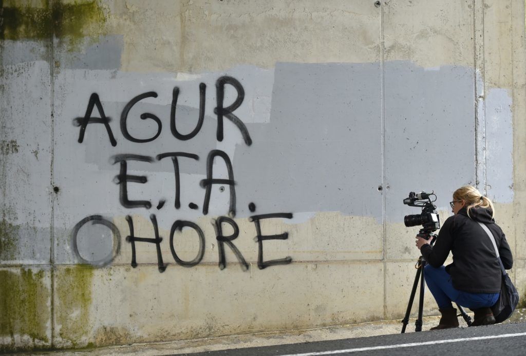 A woman takes images of a graffiti reading in Basque 