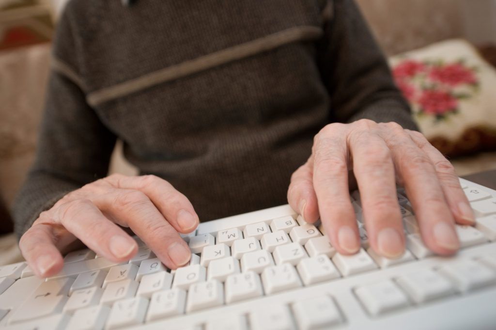 Hands of elderly person on a computer keyboard