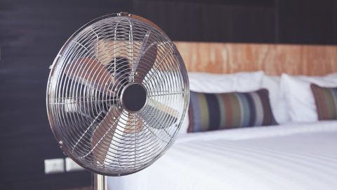 Old electric fan near the bed in the room