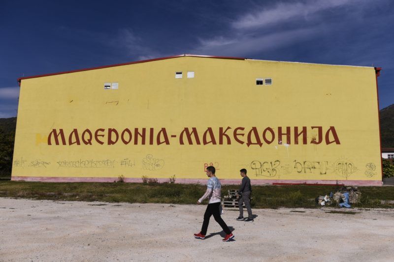 Albanian boys walk past a building reading "Macedonia" in Albanian and Macedonian in the village of Poroj, near Tetovo town, on September 28, 2018, ahead of a referendum on wether to change the country's name to "Republic of Northern Macedonia". 
Voters across the Balkan state of Macedonia will decide on September 30, 2018 whether to re-name their country North Macedonia, an emotional vote that could end a bitter row with Greece and unlock a path to NATO and the EU. It is a loaded question for many in the nation of around 2.1 million, which has tussled with Greece for 27 years over its name and history. / AFP PHOTO / Armend NIMANI
