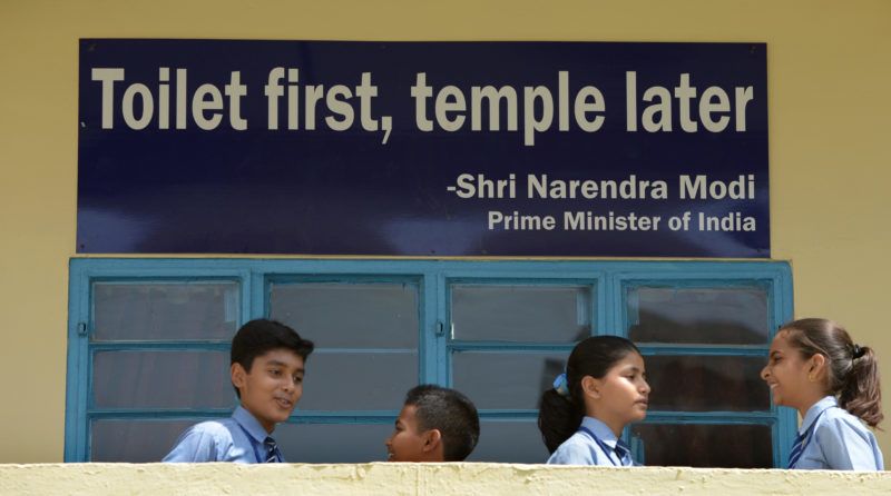 TO GO WITH India-sanitation-social-toilet-Gandhi,FOCUS BY ABHAYA SRIVASTAVA 
In this photograph taken on September 22, 2014, Indian schoolchildren talk in front of a poster bearing a quote from Prime Minister Narendra Modi at a school run by sanitation charity Sulabh International in New Delhi. Surrounded by latrines and soap dispensers, charity founder Bindeshwar Pathak is most at home in the toilet, one of which he vows to build in every impoverished home in India.  AFP PHOTO/SAJJAD HUSSAIN (Photo by SAJJAD HUSSAIN / AFP)