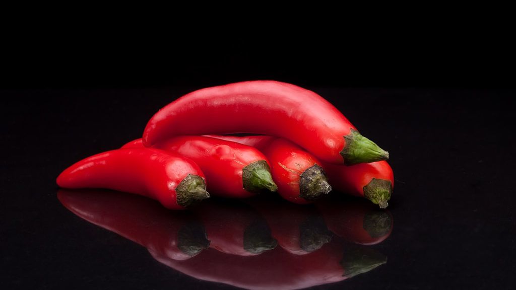Red chili pepper on black mirror background. Fresh and organic food concept