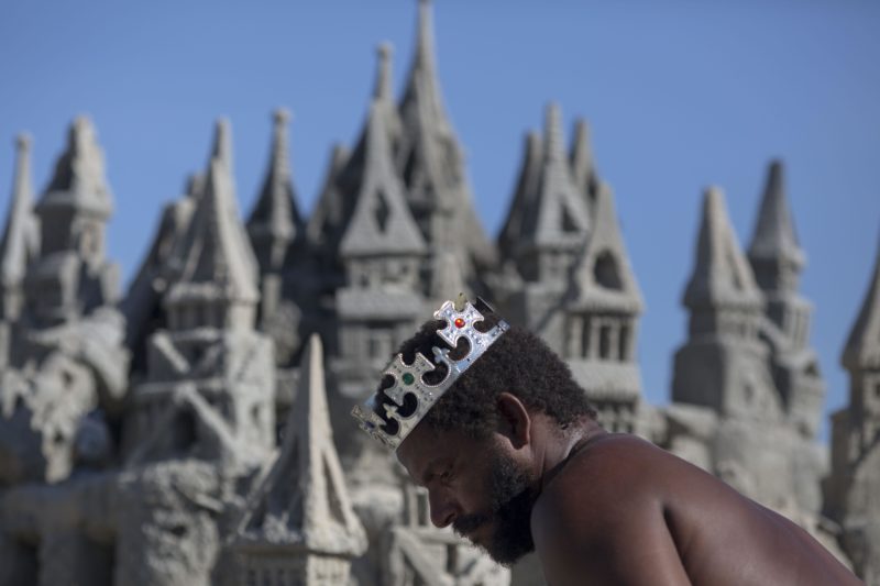 With a crown on his head, Marcio Mizael Matolias, 44, works on his sand castle despite the 40-degree heat that punishes bathers on a sunny summer afternoon on the beach of Barra da Tijuca in Rio de Janeiro, Brazil, on January 18, 2018. 
For the last 22 years, Matolias has lived inside his sand castle surrounded by books, golf clubs and fishing poles. Neighbors and friends call him "The King".  / AFP PHOTO / MAURO PIMENTEL