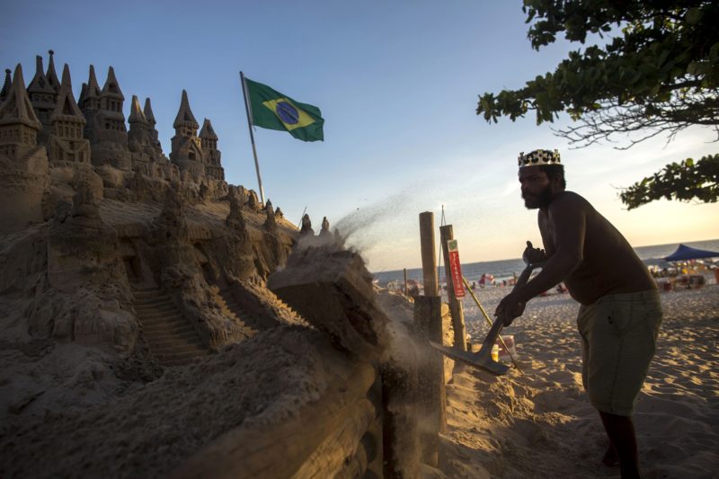With a crown on his head, Marcio Mizael Matolias, 44, works on his sand castle despite the 40-degree heat that punishes bathers on a sunny summer afternoon on the beach of Barra da Tijuca in Rio de Janeiro, Brazil, on January 18, 2018. 
For the last 22 years, Matolias has lived inside his sand castle surrounded by books, golf clubs and fishing poles. Neighbors and friends call him "The King".  / AFP PHOTO / MAURO PIMENTEL
